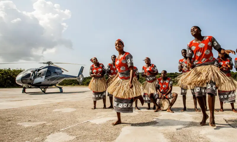Dancers in red kapulana welcoming a helicopter on a Mozambique airstrip
