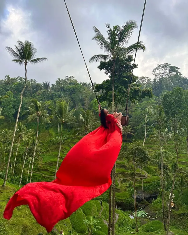 A woman in a red dress on a swing over the jungle in Bali